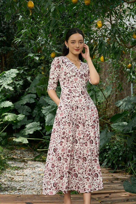Woman wearing a floral print midi cheongsam dress with elbow sleeves in a lush garden