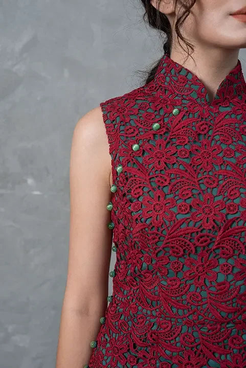 Sleeveless red lace cheongsam with floral pattern and green buttons, modern elegant style