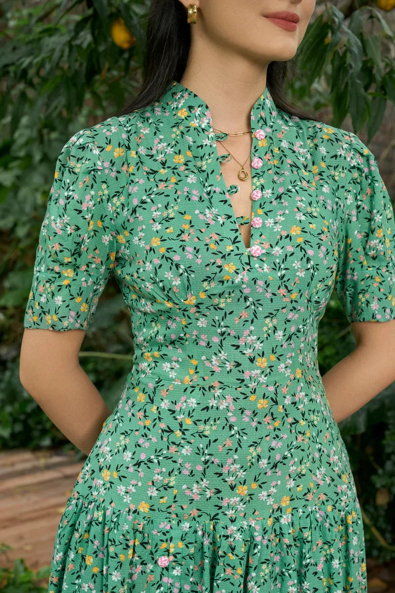 Woman wearing green floral modern cheongsam dress with short sleeves and pink buttons