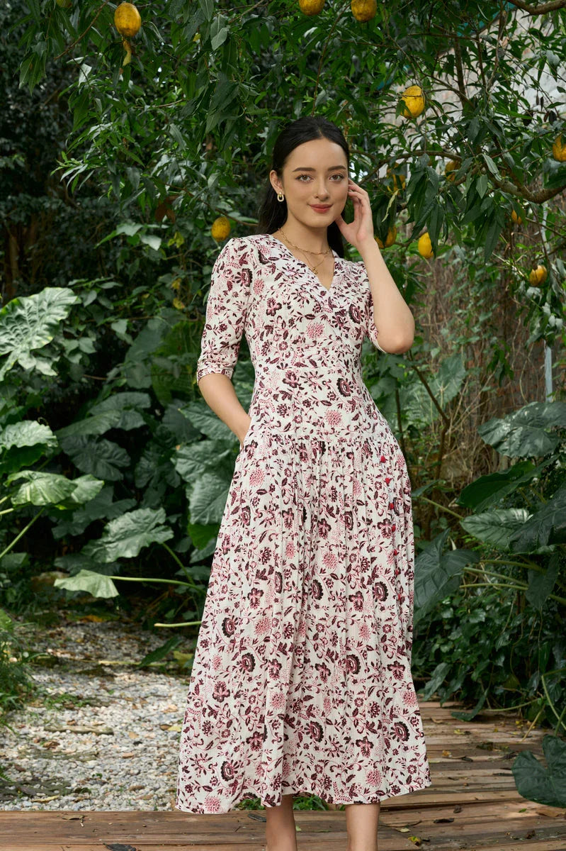 Woman wearing a floral print midi cheongsam dress with elbow sleeves in a lush garden