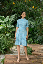 Woman in blue cheongsam-inspired midi dress with white pattern standing outdoors