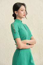 Woman in elegant green modern cheongsam dress with pearl button sleeve detail