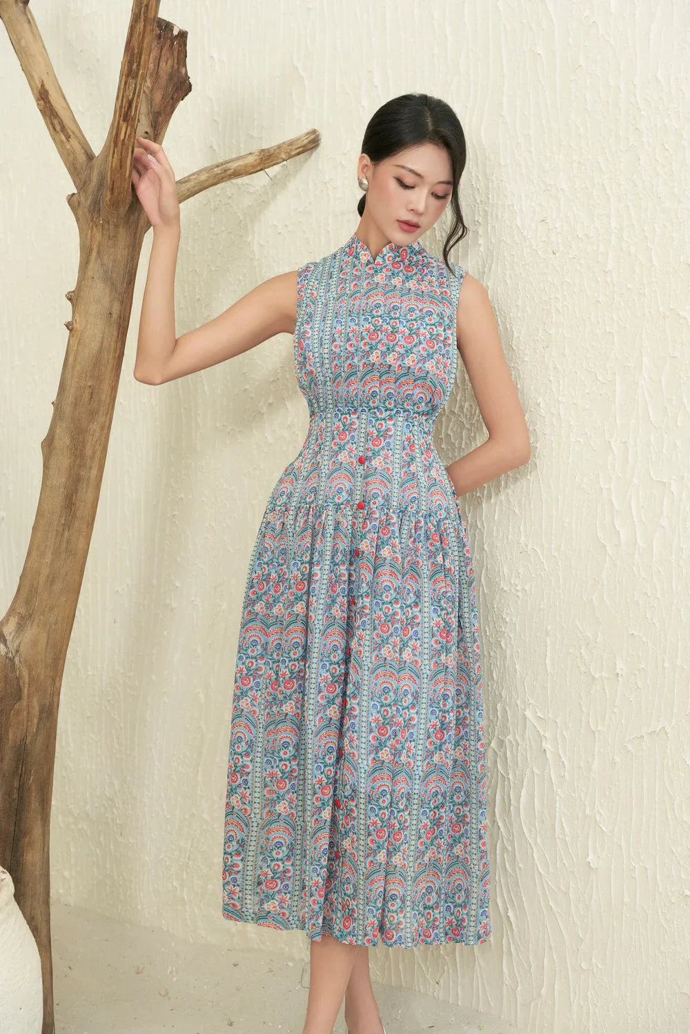 Woman in sleeveless floral modern cheongsam dress with fitted waist, standing indoors