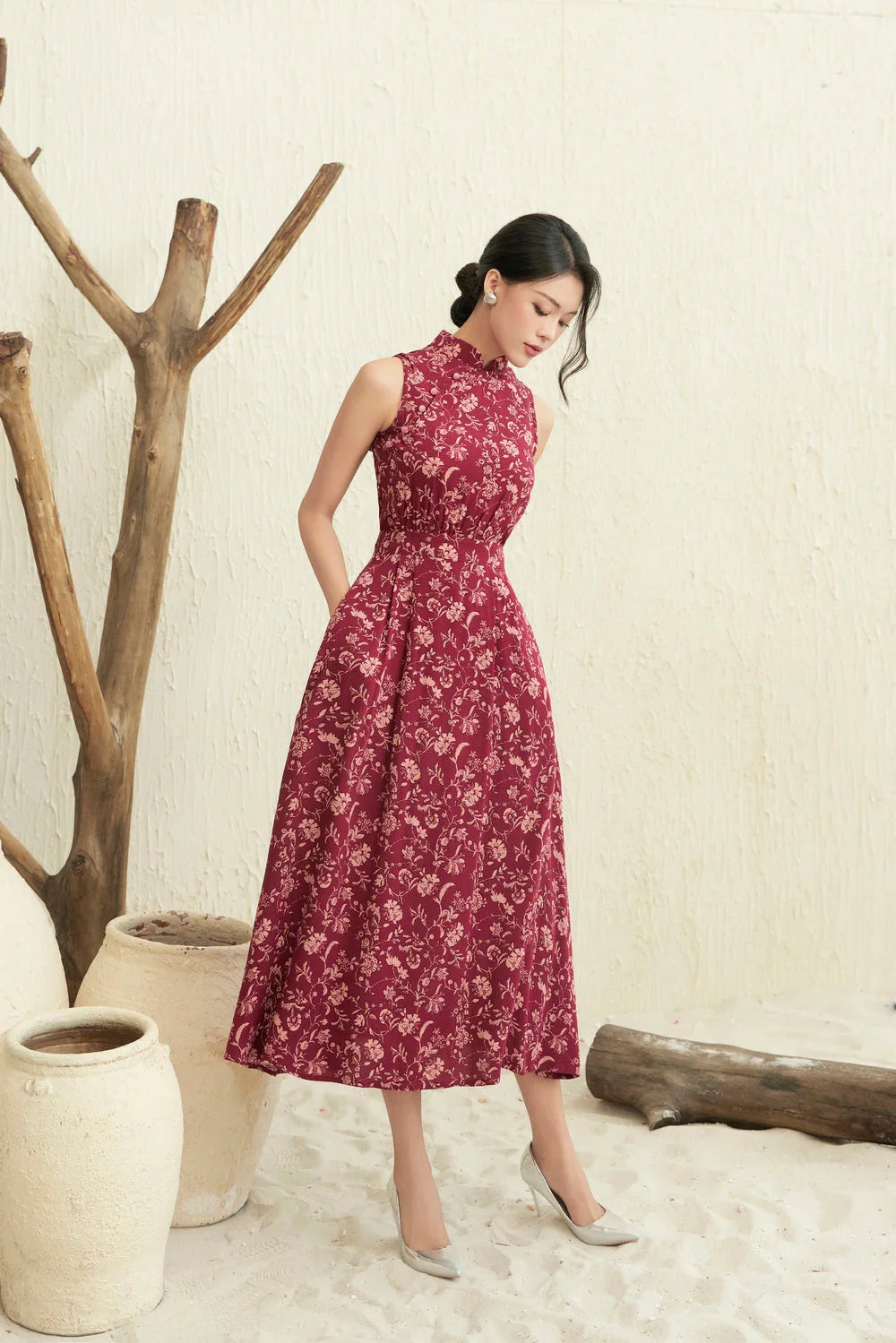 Woman in elegant sleeveless red floral cheongsam dress, indoor neutral setting, mid-length style