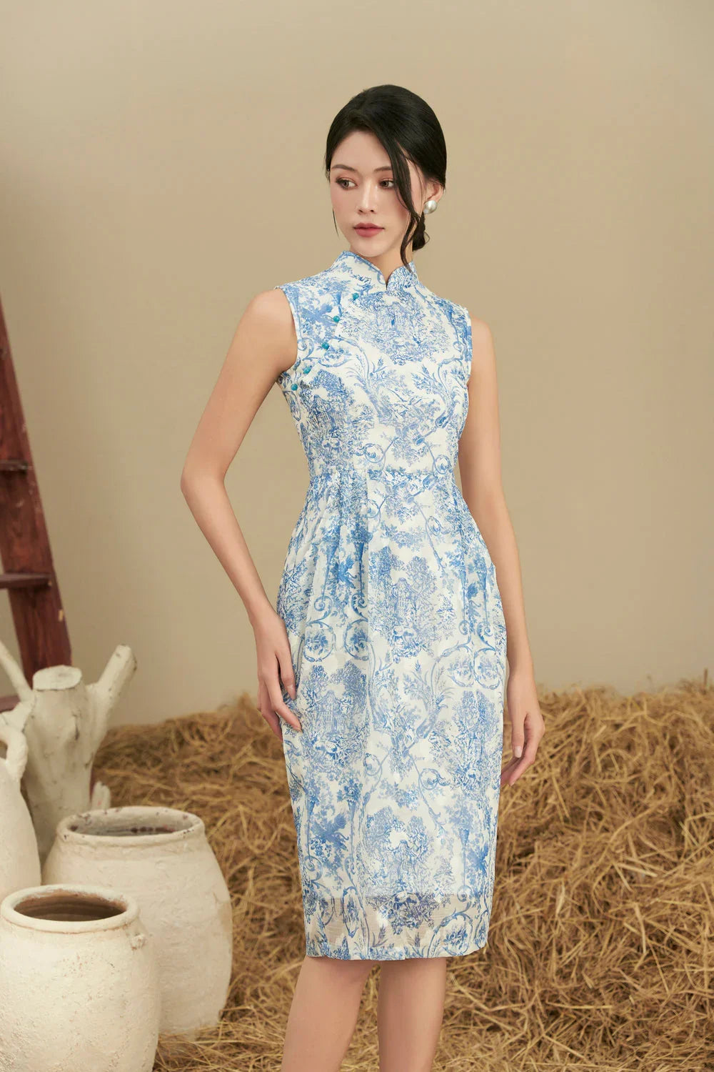 Woman wearing blue and white printed cheongsam dress with mandarin collar, rustic background