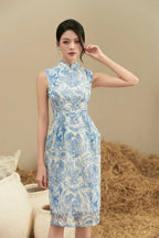 Woman wearing a sleeveless blue and white floral cheongsam dress, standing indoors.