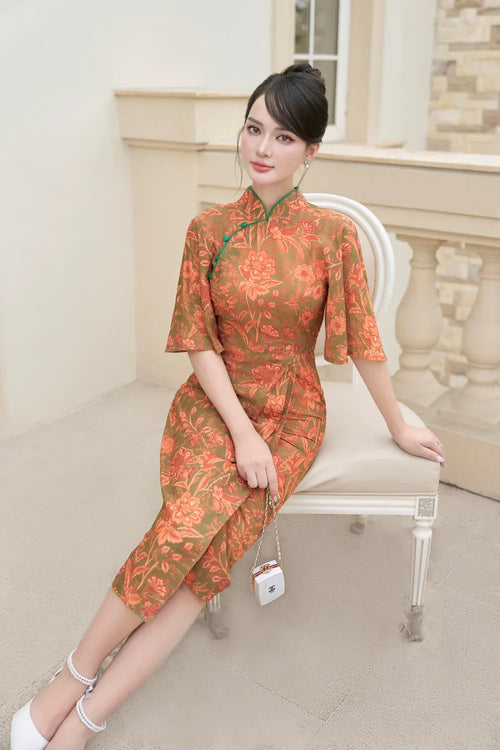 Woman in elegant modern floral cheongsam with half sleeves, sitting on a white chair outdoors