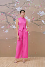 Woman wearing a modern pink cheongsam-inspired sleeveless top and matching wide-leg pants.