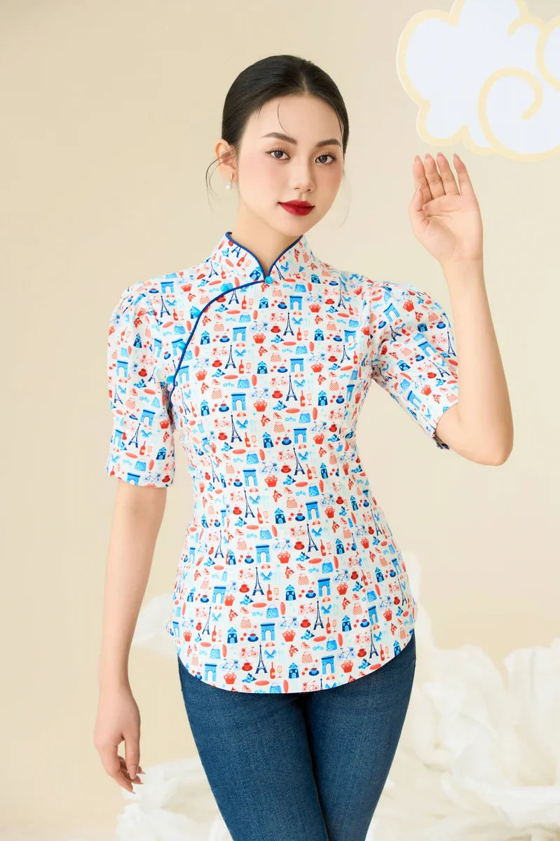 Woman wearing modern cheongsam top with colorful Paris-inspired print and blue trim, paired with jeans.