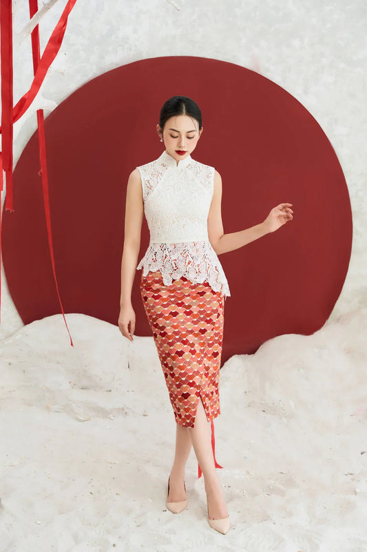 Woman in a modern lace cheongsam dress with red patterned skirt, standing against a red circle backdrop.