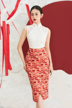 Woman in modern cheongsam with white lace top and red patterned skirt, standing indoors