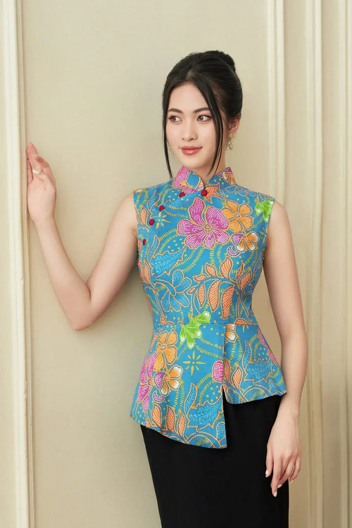 Woman wearing modern sleeveless floral cheongsam with blue, orange, and pink patterns