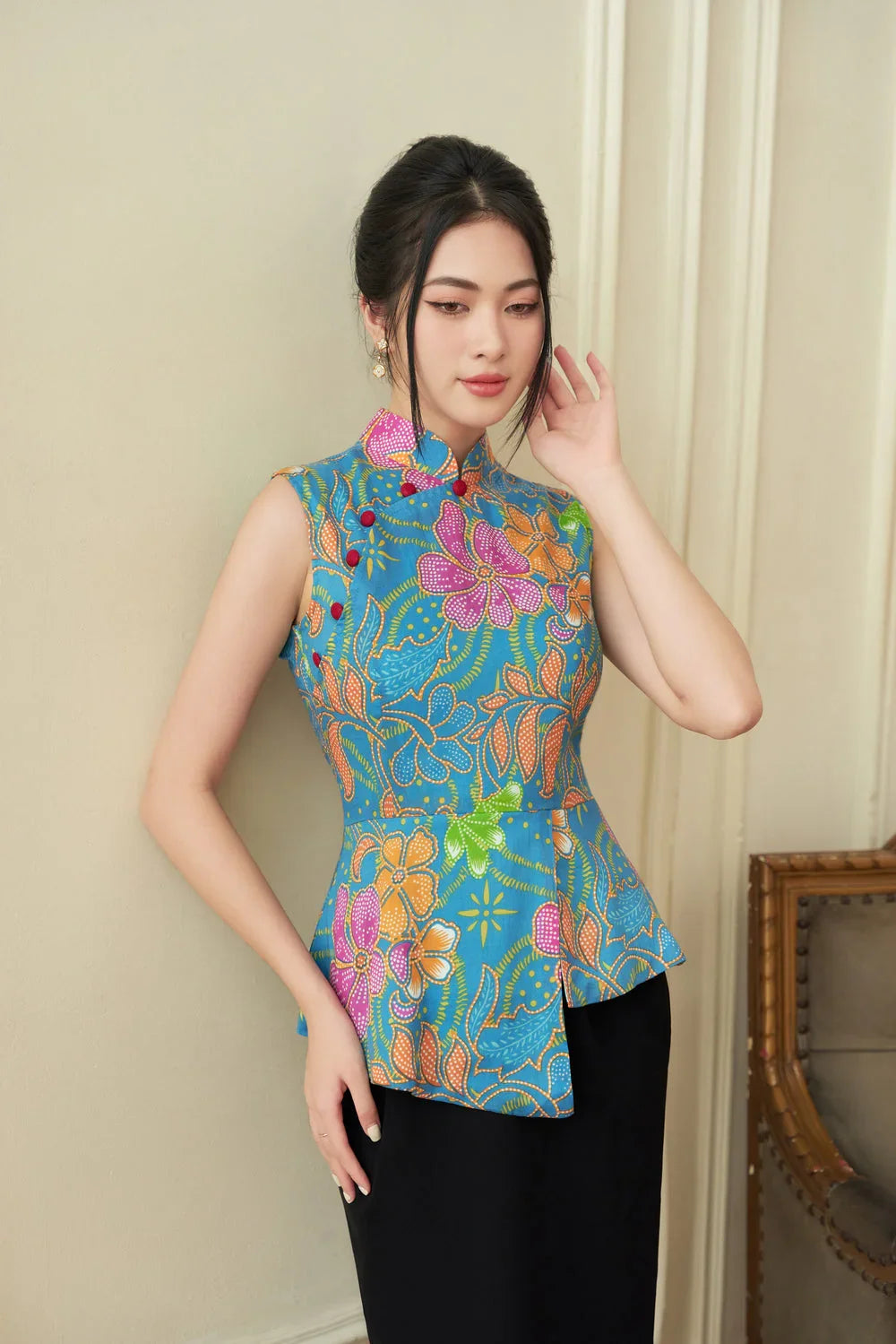 Woman wearing a modern sleeveless cheongsam with vibrant floral print and mandarin collar