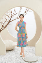 Woman in modern blue floral cheongsam dress, standing in minimalist setting with white blossom branches